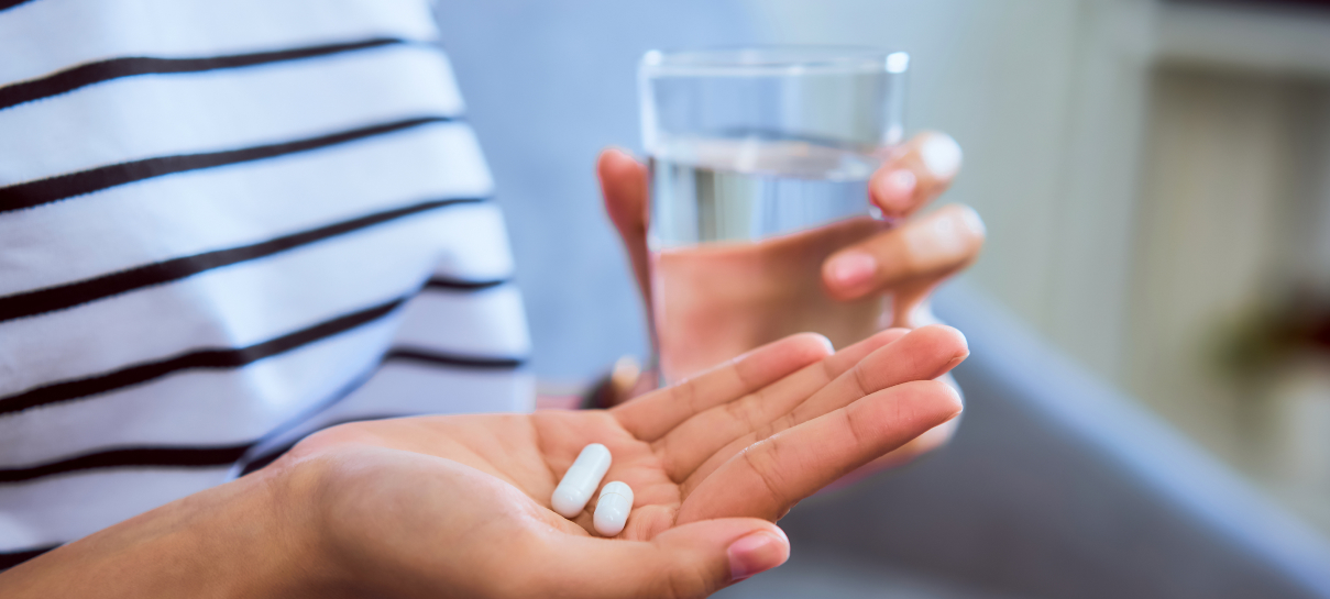 a woman holding a glass of water and pills