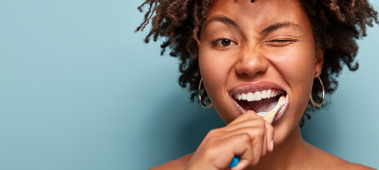 a woman brushing her teeth with a toothbrush